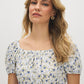 Snow White Ditsy Print Mini Dress - Woman Wearing Off-the-Shoulder Tiered Dress - Suzy Shier